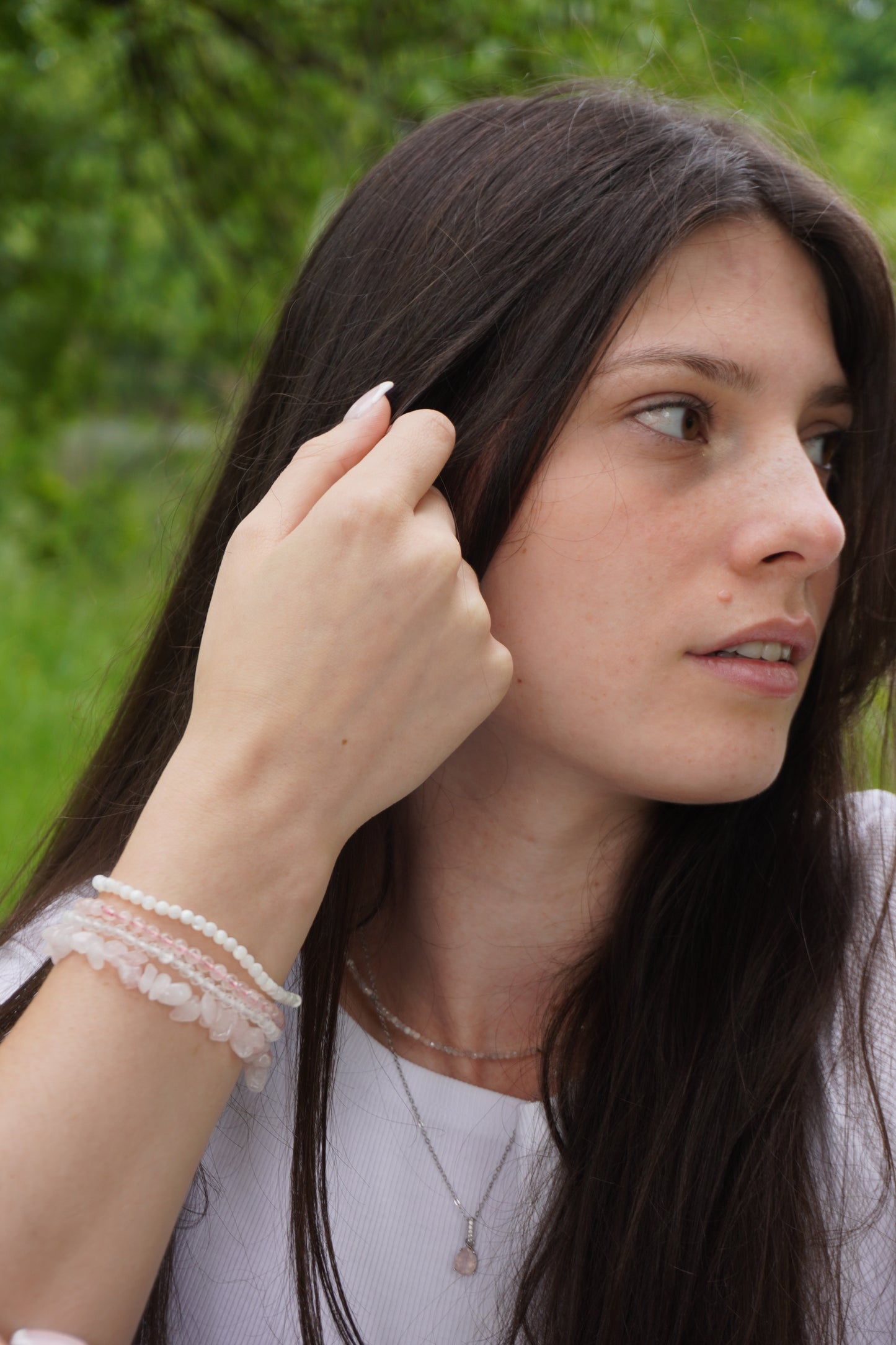 Frau mit zarten Edelsteinarmbändern aus Perlmutt, Rosenquarz und Bergkristall.