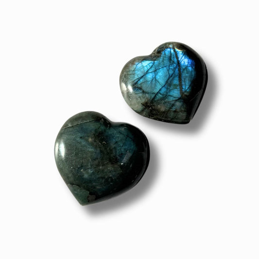 Herzförmiger Labradorit mit schimmerndem Farbspiel in blau, auf hellem Hintergrund.