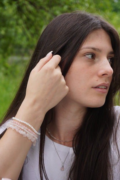 Frau mit zarten Edelsteinarmbändern aus Perlmutt, Rosenquarz und Bergkristall.