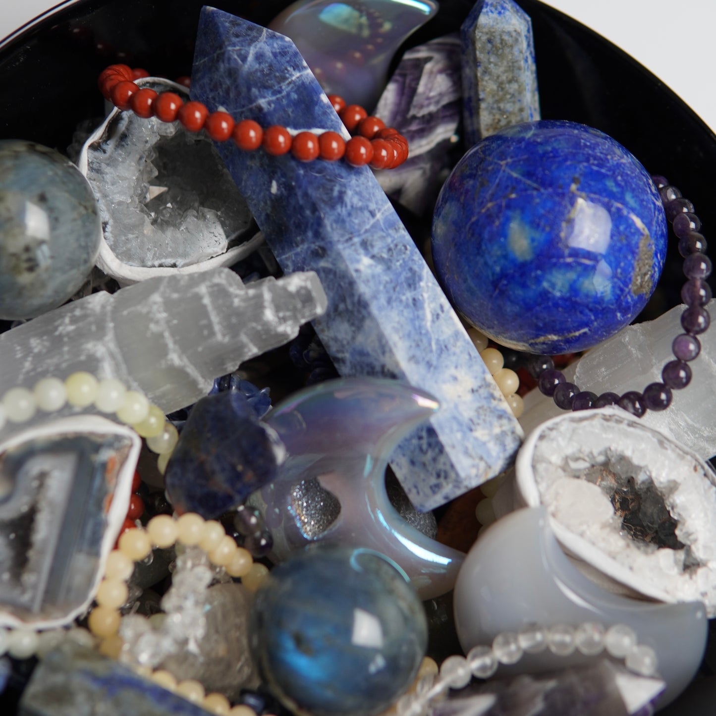 Detailaufnahme eines Edelsteinscoops von Januar mit glänzenden, polierten Kristallen in intensiven Farben und unterschiedlichen Formen, die im Licht schimmern.