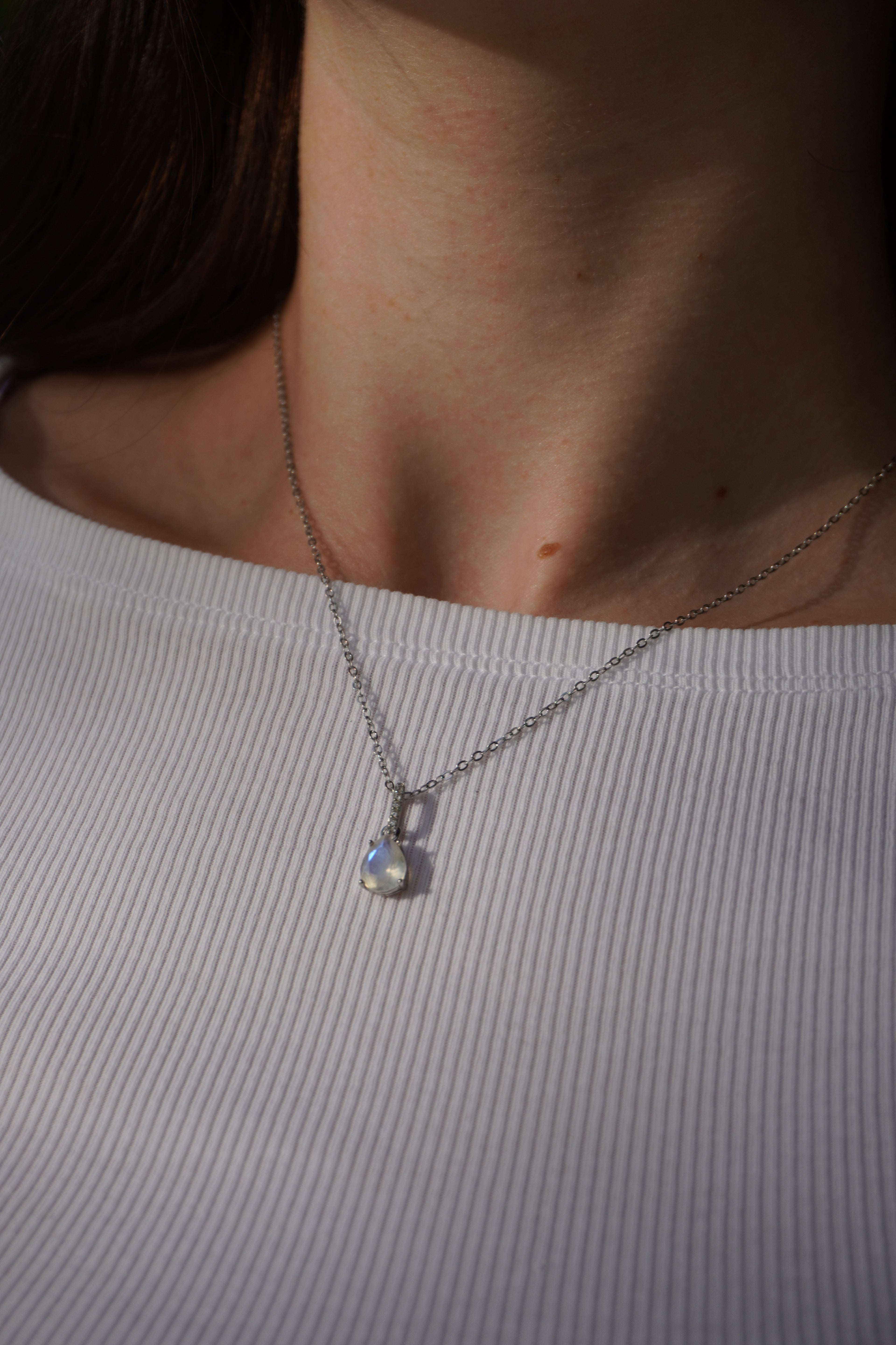 Zarte Halskette mit Mondstein und Zirkonia-Tropfenanhänger an Silber Kette. getragen an weiblichem Hals, für Intuition, Schutz und feminine Energie.