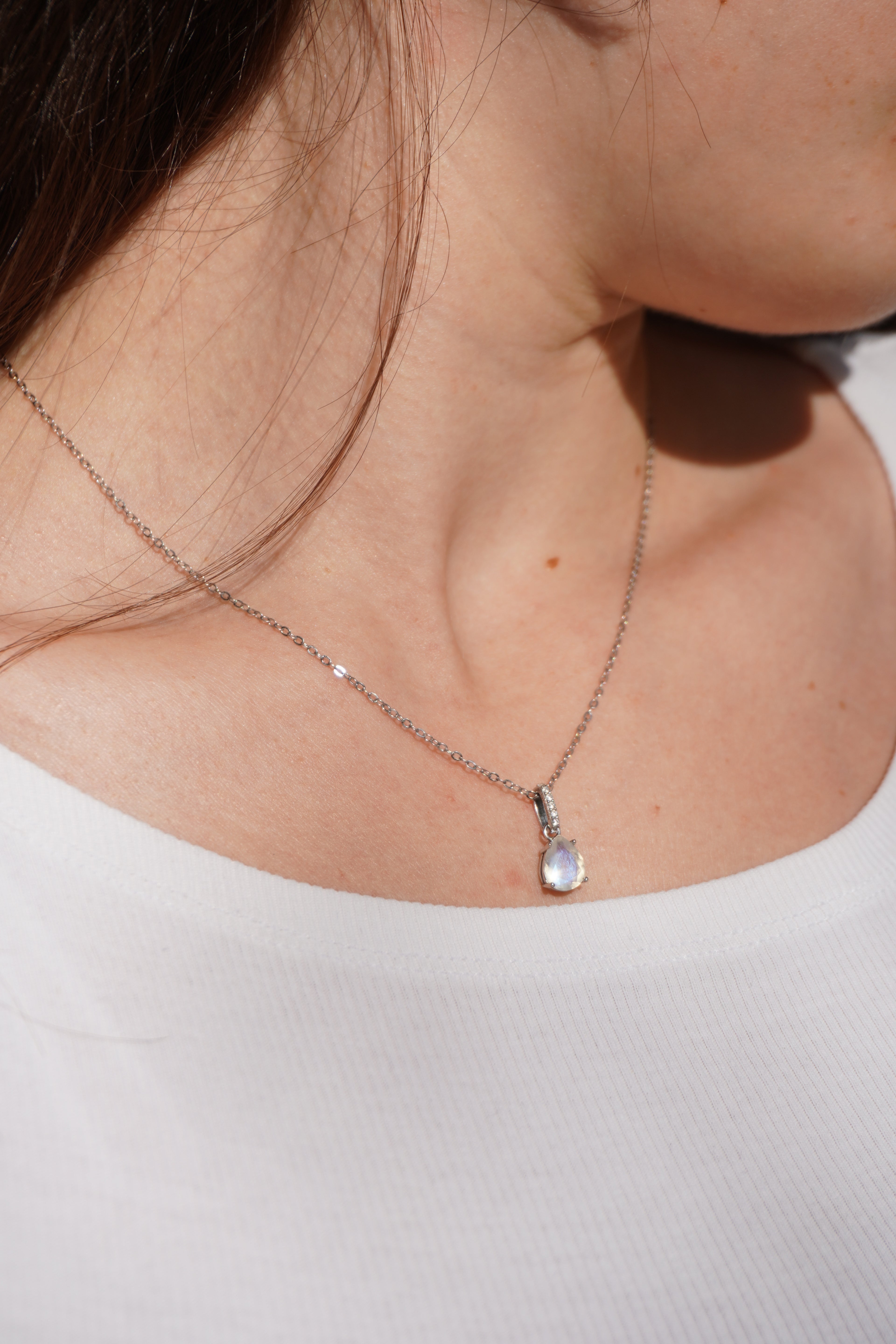 Zarte Halskette mit Mondstein und Zirkonia-Tropfenanhänger an Silber Kette. getragen an weiblichem Hals, für Intuition, Schutz und feminine Energie.