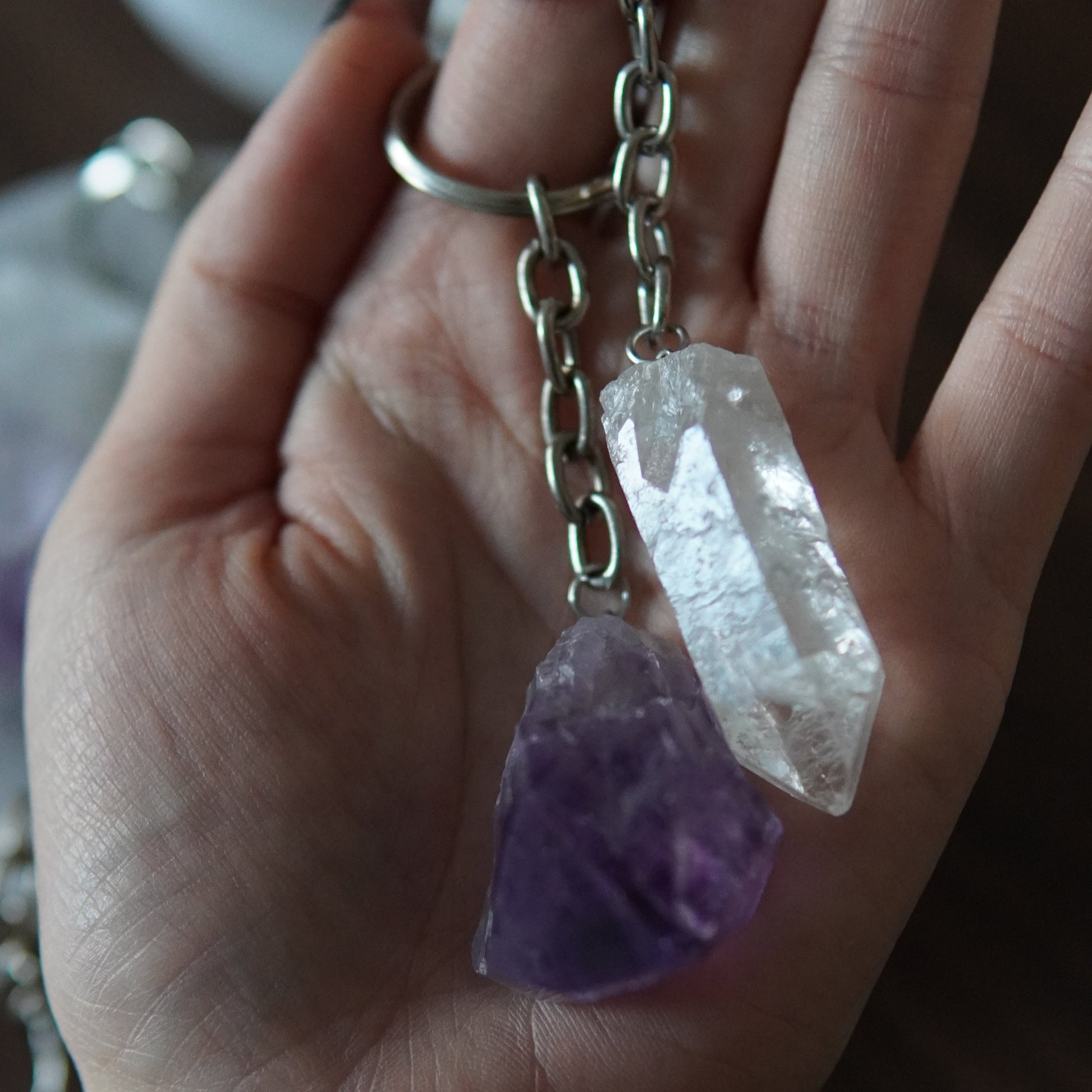 Bergkristallspitze und lila Amethystspitze als Schlüsselanhänger in Handfläche liegend. 