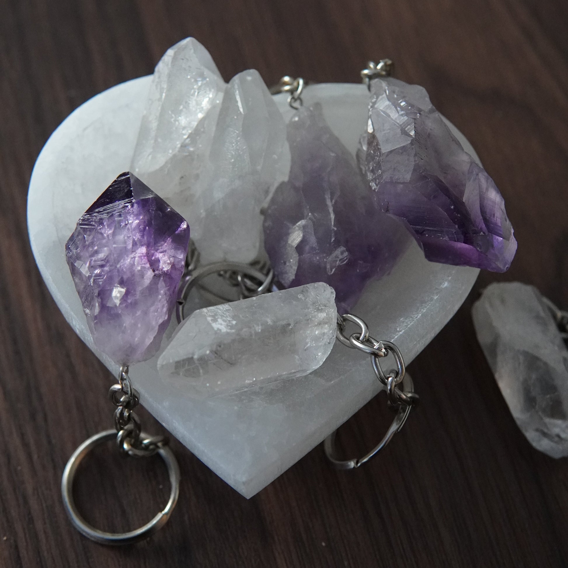 Rohstein Schlüsselanhänger aus Amethyst und Bergkristall, Heilstein Anhänger dekorativ präsentiert in herzförmiger Selinit Schale.