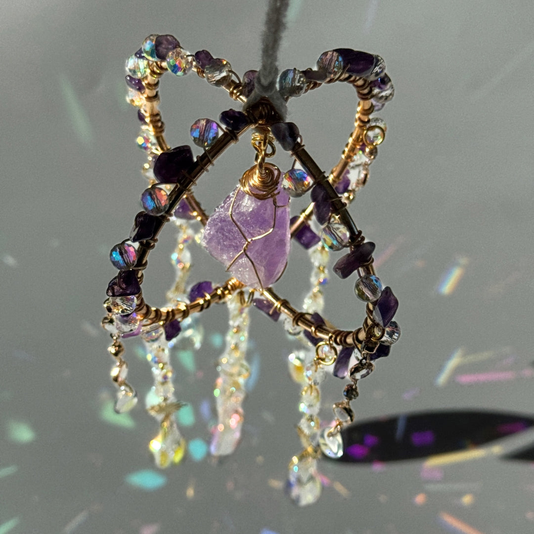 Sonnenfänger mit Amathyst, eingefasst in violetter Drahtoptik und Kristall-Elementen – lebendige Lichtfänger-Deko mit Edelsteinen für spirituelle Räume oder als Geschenk.