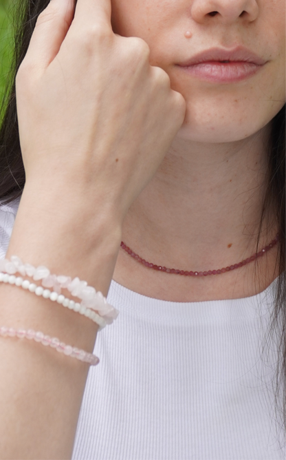Nahaufnahme einer jungen Frau mit zarten Edelsteinarmbändern aus Rosenquarz und Perlmutt sowie einer Halskette aus facettiertem pinkem Turmalin – handgefertigter Schmuck für Selbstliebe, Herzöffnung und emotionale Stärke.