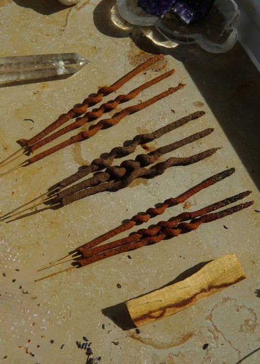 Räucherstäbchen-Set mit 9 Stäbchen und einem Palo-Santo-Holz, ordentlich nebeneinander angeordnet.